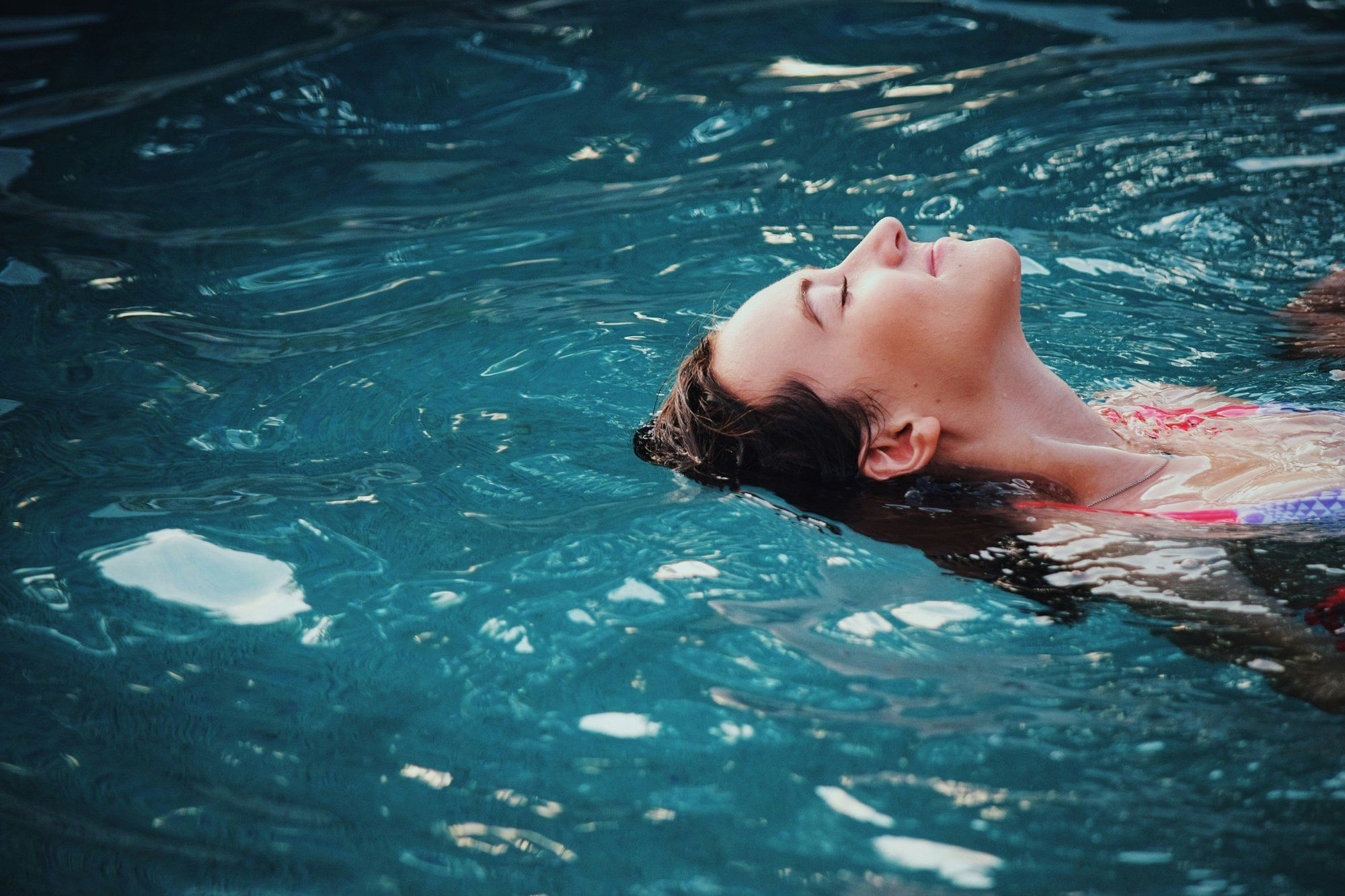 Woman floating in water with eyes closed, a way to regulate the nervous system