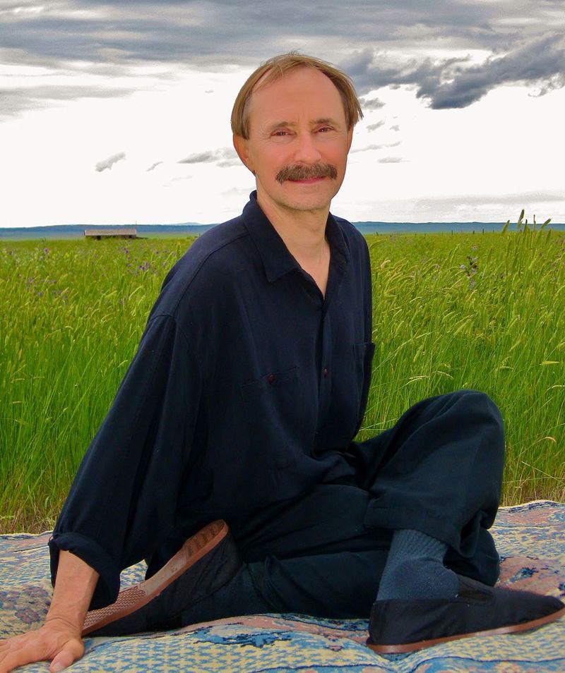 Paulie Zink, founder of yin yoga, sitting cross-legged in a field